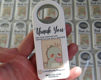 May include: White bottle opener with a metal loop, featuring a cartoon dinosaur holding a heart. The text reads "Thank You" and "FOR YOUR PURCHASE AND SUPPORTING OUR SMALL BUSINESS!" with the Little Panda Magnet logo.