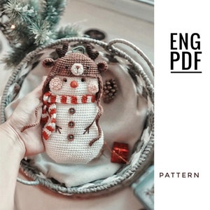 May include: Crochet amigurumi pattern for a snowman wearing a reindeer hat and scarf. The pattern is available in English and is in PDF format.