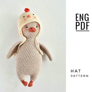 Puede incluir: Patrón de crochet para un adorable juguete amigurumi de pollito con sombrero. El patrón está escrito en inglés y está disponible para descargar en PDF. El pollito es beige con patas naranjas y un pico rojo. El sombrero es crema con un pompón rojo.
