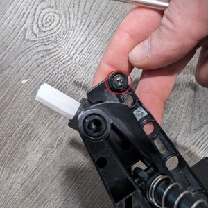 Puede incluir: Primer plano de una pieza de pl&aacute;stico negro con un muelle met&aacute;lico y un peque&ntilde;o tornillo plateado. El tornillo est&aacute; rodeado de un c&iacute;rculo rojo.