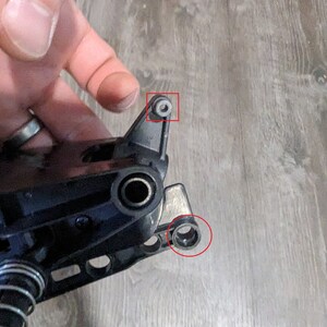 Puede incluir: Primer plano de una pieza de pl&aacute;stico negro con un resorte met&aacute;lico y dos anillos met&aacute;licos. La pieza tiene un peque&ntilde;o pasador met&aacute;lico en la parte superior.