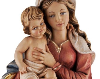 Puede incluir: Estatua de madera tallada que representa a una mujer sosteniendo a un niño. La mujer viste una túnica roja y azul con detalles dorados. El niño está desnudo y la estatua se encuentra sobre una base decorativa.