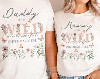 Puede incluir: Dos camisetas blancas con diseños florales y texto que dice "Daddy of the Wild and Onederful Birthday Girl" y "Mommy of the Wild and Onederful Birthday Girl".
