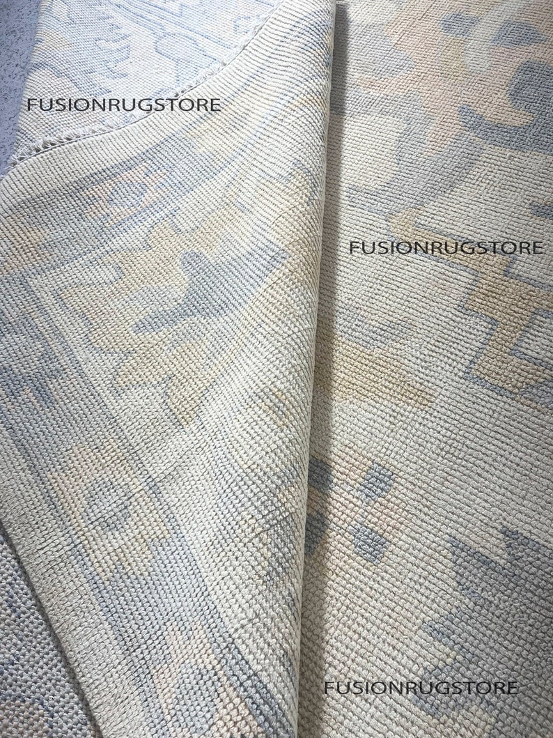 Może przedstawiać: Zbliżenie na jasnoniebieski i kremowy dywan z tekstem "Fusionrugstore" powt&oacute;rzonym trzy razy.