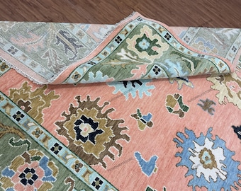 May include: A pink and green patterned rug with a floral design. The rug has a fringed edge and is folded in half.