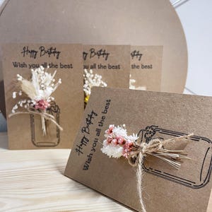 Tarjeta plegable de papel kraft con flores secas y cuerda de yute para diversas ocasiones.