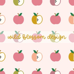 Op de afbeelding: Een herhalend patroon op een lichtroze achtergrond met hele en gehalveerde appels in roze, groene en gouden tinten, elk met een klein groen blaadje. De tekst "wild blossom design" staat in een goudkleurig cursief lettertype in het midden.