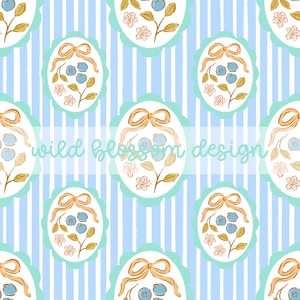May include: A repeating pattern featuring oval frames with blueberries, bows, and floral accents on a striped blue and white background. The text "wild blossom design" is overlaid on the image.