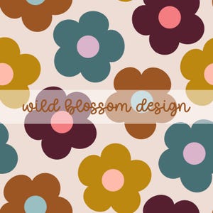 Op de afbeelding: Een herhalend patroon van grote, gestileerde bloemen in tinten bruin, blauwgroen, mosterdgeel en bordeaux, elk met een contrasterend roze of lichtblauw centrum. De bloemen staan tegen een lichtroze achtergrond. De tekst "wild blossom design" is over de afbeelding gelegd.