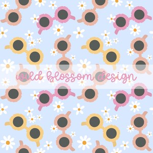 Op de afbeelding: Een naadloos patroon met roze en gele zonnebrillen met ronde glazen en witte madeliefjes op een lichtblauwe achtergrond. De tekst "wild blossom design" staat in een witte banner in het midden van het patroon.