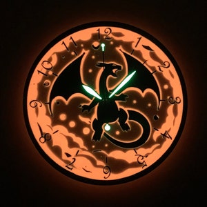 May include: A glow-in-the-dark clock with a black dragon silhouette and orange glow-in-the-dark numbers. The clock hands are green and glow in the dark.