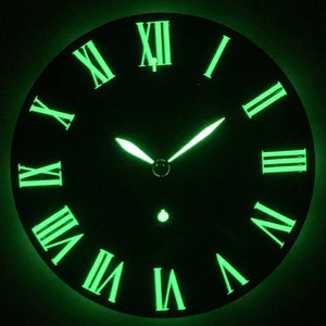 May include: A black clock face with glow-in-the-dark Roman numeral hour markers and green hands. The clock face is illuminated in green.