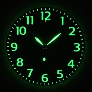 Può includere: Un quadrante rotondo con numeri e lancette verdi luminose su sfondo nero. I numeri da 1 a 12 sono uniformemente distanziati attorno al perimetro. Le lancette delle ore e dei minuti indicano circa l'1:09.