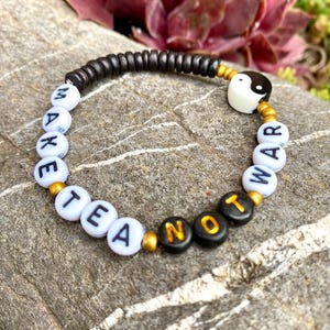 Pulsera con mensaje "Haz té, no la guerra" | Joyería de paz hecha a mano con yin-yang de porcelana | Cuentas de madera y acrílico