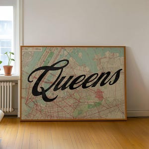 May include: A framed map of Queens, New York, with the word "Queens" in large, black script. The map has a vintage aesthetic with red and green details, set in a room with hardwood floors and a window.