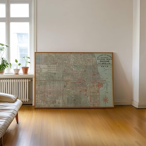 May include: A framed vintage map of Chicago, Illinois, in a wooden frame. The map shows a detailed layout of the city with red and green lines indicating streets and railways. The text "Railway Guide Map Chicago" is visible.