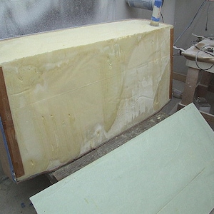 Pode incluir: Estrutura retangular em constru&ccedil;&atilde;o, provavelmente um casco de barco. O n&uacute;cleo &eacute; uma espuma espessa amarelo claro, emoldurada com madeira e fita azul. Um painel verde claro est&aacute; por perto.