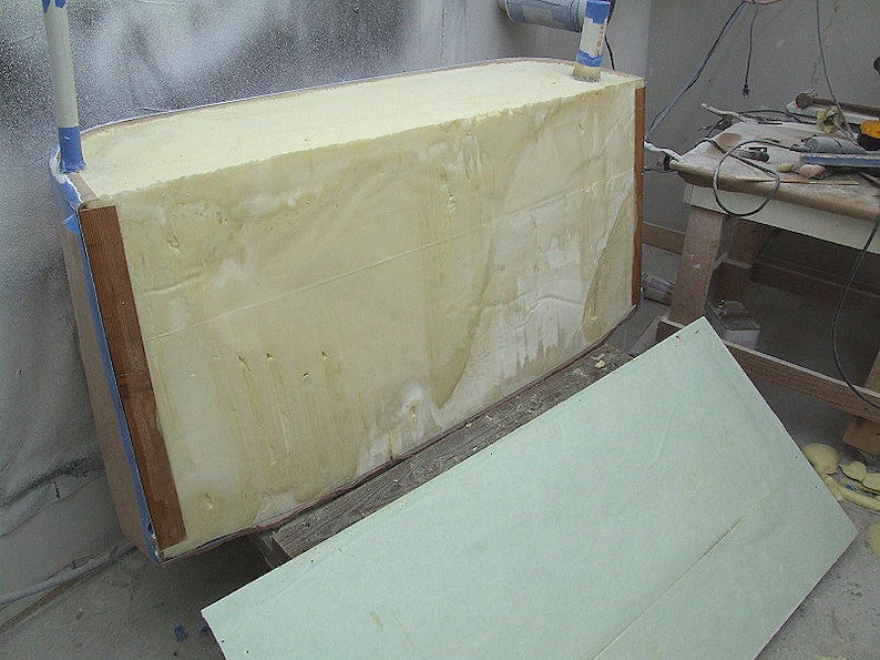 Pode incluir: Estrutura retangular em constru&ccedil;&atilde;o, provavelmente um casco de barco. O n&uacute;cleo &eacute; uma espuma espessa amarelo claro, emoldurada com madeira e fita azul. Um painel verde claro est&aacute; por perto.