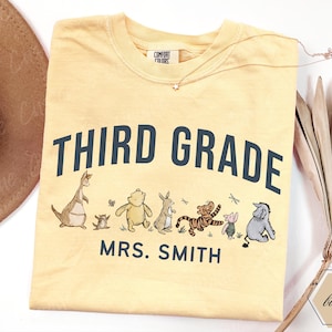 May include: A butter yellow t-shirt featuring the dark blue text THIRD GRADE and MRS. SMITH, accompanied by a graphic illustration of Winnie the Pooh characters including Roo, Roo's mother, Pooh, Rabbit, Tigger, Piglet, and Eeyore in a line.