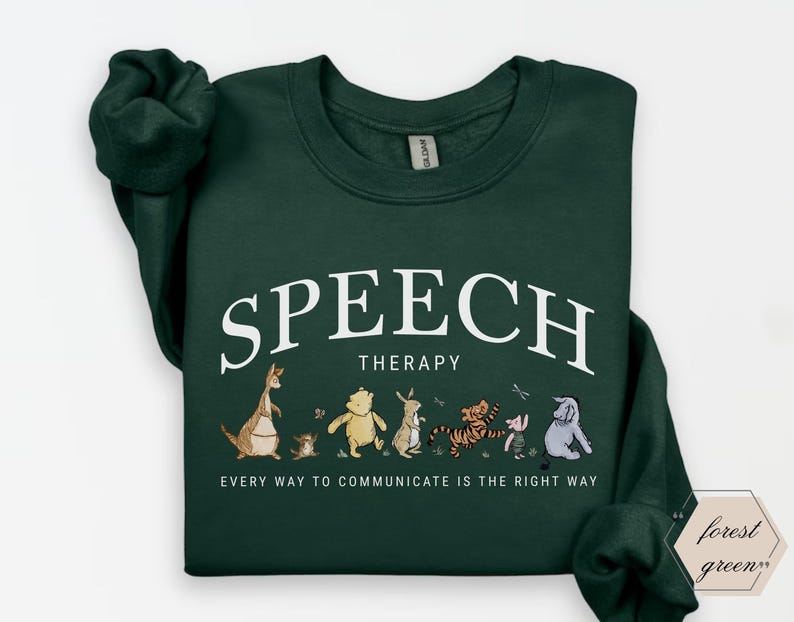 May include: Forest green sweatshirt with the words "SPEECH THERAPY" in white arched text above a line of cartoon characters. Below the text is the phrase "EVERY WAY TO COMMUNICATE IS THE RIGHT WAY".