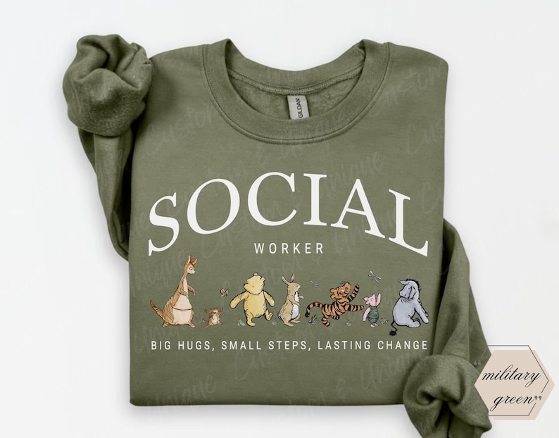 Pu&ograve; includere: Felpa verde oliva con la scritta bianca "SOCIAL WORKER" e personaggi dei cartoni animati. Sotto c'&egrave; la frase "BIG HUGS, SMALL STEPS, LASTING CHANGE". La felpa &egrave; di colore verde militare.