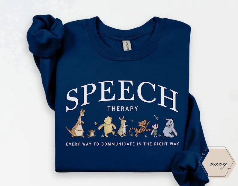 May include: Navy blue sweatshirt with the words "SPEECH THERAPY" in white arched text. Below the text is a line of cartoon characters. The phrase "EVERY WAY TO COMMUNICATE IS THE RIGHT WAY" is printed below the characters.