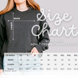 May include: A dark gray Gildan 18000 adult crewneck sweatshirt with a size chart. The chart shows measurements in inches for width, length, and sleeve center back, ranging from XS to 5XL. The text "Size Chart" is in a script font.