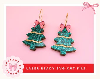 May include: A pair of Christmas tree earrings with a glittery green finish and gold accents. Each earring features a pink bow at the top and hangs from a gold hoop. The text "LASER READY SVG CUT FILE" is visible.