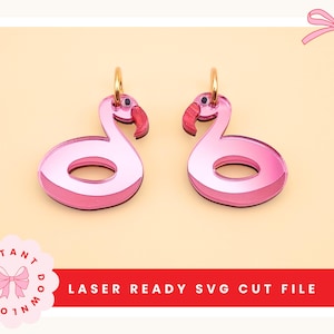May include: Two pink flamingo earrings with gold-colored hoops. The earrings are laser-cut with a mirrored finish, featuring a flamingo shape with a red beak. The background is a light beige color. Text at the bottom reads "LASER READY SVG CUT FILE".