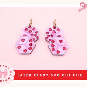 May include: Two pairs of pink and red heart-shaped earrings with gold hoops. The earrings are hexagonal and feature a pattern of red hearts. The image also includes the text "LASER READY SVG CUT FILE".