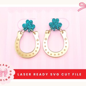 Könnte beinhalten: Goldene Hufeisen-Ohrringe mit einem teal-farbenen Glitzer-Kleeblatt-Akzent. Die Ohrringe haben ein gepunktetes Muster und kleine Blumendetails. Der Text "LASER READY SVG CUT FILE" ist ebenfalls enthalten.