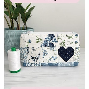 May include: A blue and white patchwork fabric pouch with a heart-shaped patch. The pouch is 4.5 inches by 9 inches by 3 inches. The pouch is labeled "Candy Cordial Pouch" and "Mini Charm Friendly".