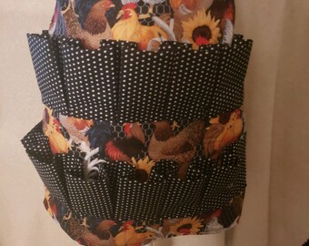 May include: Black and white polka dot apron with multiple pockets. The apron has a top section with a chicken and sunflower print.