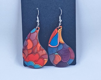 May include: A pair of teardrop-shaped earrings with a colorful, abstract design. The earrings feature a mix of red, orange, blue, and purple hues, with silver-colored ear wires. The earrings are displayed against a dark background.