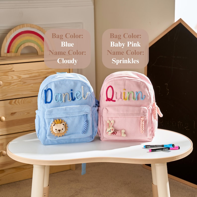 May include: Two corduroy backpacks, one blue with the name Daniel in blue and a lion patch, and one baby pink with the name Quinn in rainbow colours and a rabbit patch. Text labels indicate Bag Colour: Blue, Name Colour: Cloudy and Bag Colour: Baby Pink, Name Colour: Sprinkles.