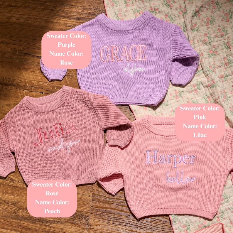May include: Three pastel-coloured knit sweaters with embroidered names. The purple sweater says "GRACE", the pink sweater says "HARPER", and the rose sweater says "Julia". The sweaters are on a wooden surface.