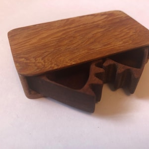 May include: A wooden box with a hinged lid and a unique, intricate interior design. The box is made of light brown wood with a natural grain pattern.