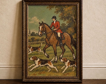 May include: A framed oil painting depicting a rider in a red hunting coat mounted on a brown horse, accompanied by three hounds running through a grassy field. The scene includes a distant church steeple and trees under a cloudy sky in a dark frame.