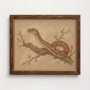 May include: A framed wall art print featuring a detailed illustration of a brown patterned snake coiled around a flowering branch with small pink blossoms. The artwork is encased in a dark, weathered wooden frame with a thin gold inner border.