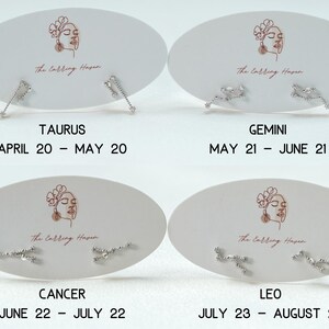 May include: Four sets of silver stud earrings on white oval cards. Each card has a line drawing of a woman's face and the text "The Calling Haven." The cards are labelled with zodiac signs: Taurus, Gemini, Cancer, and Leo, with their dates.