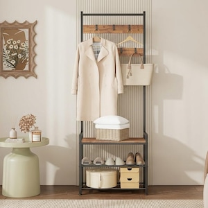 May include: A tall, black metal hall tree with wooden shelves and hooks. It features a hanging beige coat, a tote bag, and a white basket on the middle shelf. The bottom shelves hold various shoes, a round box, and two small square storage boxes.