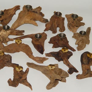 May include: A collection of 14 rustic wooden candle holders with brass candle cups. Each holder is unique in shape and size, with natural wood grain and texture.