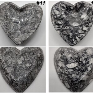 May include: Four heart-shaped decorative dishes with a marbled gray and white pattern. Each dish has a unique pattern and is labeled with a number in the top right corner. The dishes are made of a polished stone material.