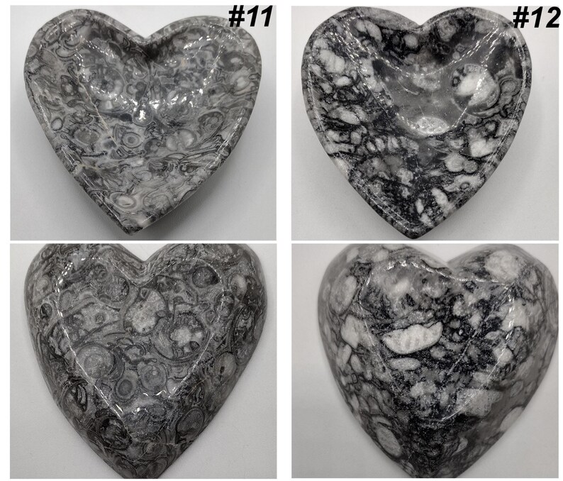 May include: Four heart-shaped decorative dishes with a marbled gray and white pattern. Each dish has a unique pattern and is labeled with a number in the top right corner. The dishes are made of a polished stone material.