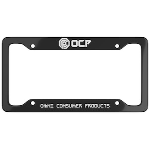 May include: Black license plate frame with the text "OCP" and "OMNI CONSUMER PRODUCTS" in white. The frame has a rectangular shape with rounded corners and four mounting holes.