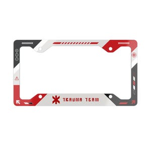 May include: A rectangular license plate frame featuring a white, red, and dark gray geometric design. The frame includes the text "TRAUMA TEAM" in red lettering, a red medical star symbol, various directional arrows, and warning icons.