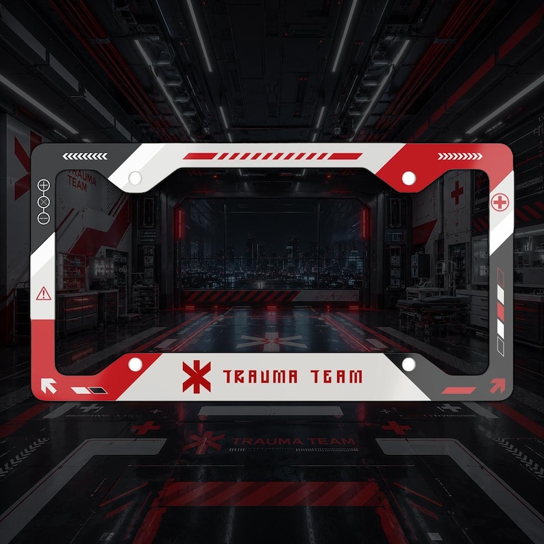 May include: A rectangular license plate frame featuring a white, red, and dark gray color scheme with geometric patterns. The frame displays the text "TRAUMA TEAM" in a bold, stylized font, accompanied by a red medical cross symbol and various icons.