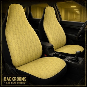 May include: A pair of car seat covers featuring a mustard yellow fabric with a repeating dark chevron pattern. The covers are fitted over the front seats of a vehicle, which have black side panels and black headrests. The text BACKROOMS CAR SEAT COVERS is visible in the bottom left corner.