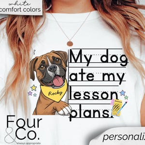 May include: White t-shirt with a cartoon illustration of a brown and white boxer dog wearing a yellow collar with the name "Rocky" on it. The text "My dog ate my lesson plans." is written in black on a white background with black lines.
