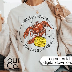 May include: A white sweatshirt with a graphic design of a red crawfish holding a yellow ear of corn. The text "BOIL & BREW CRAWFISH CREW" is printed in a black circle around the crawfish.